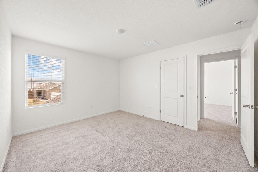 Unfurnished bedroom with light colored carpet and baseboards