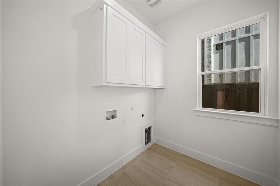 Laundry area with hookup for a gas dryer, cabinet space, hookup for an electric dryer, light tile patterned flooring, and washer hookup