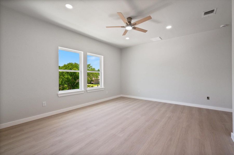 A tranquil primary bedroom with ample light and modern ceiling features.