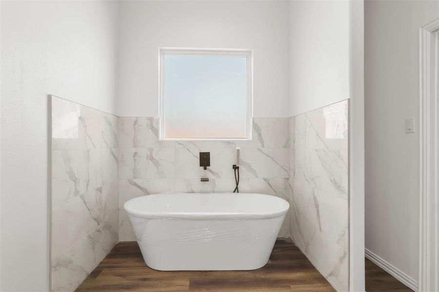 Bathroom featuring a bathing tub, hardwood / wood-style floors, and tile walls