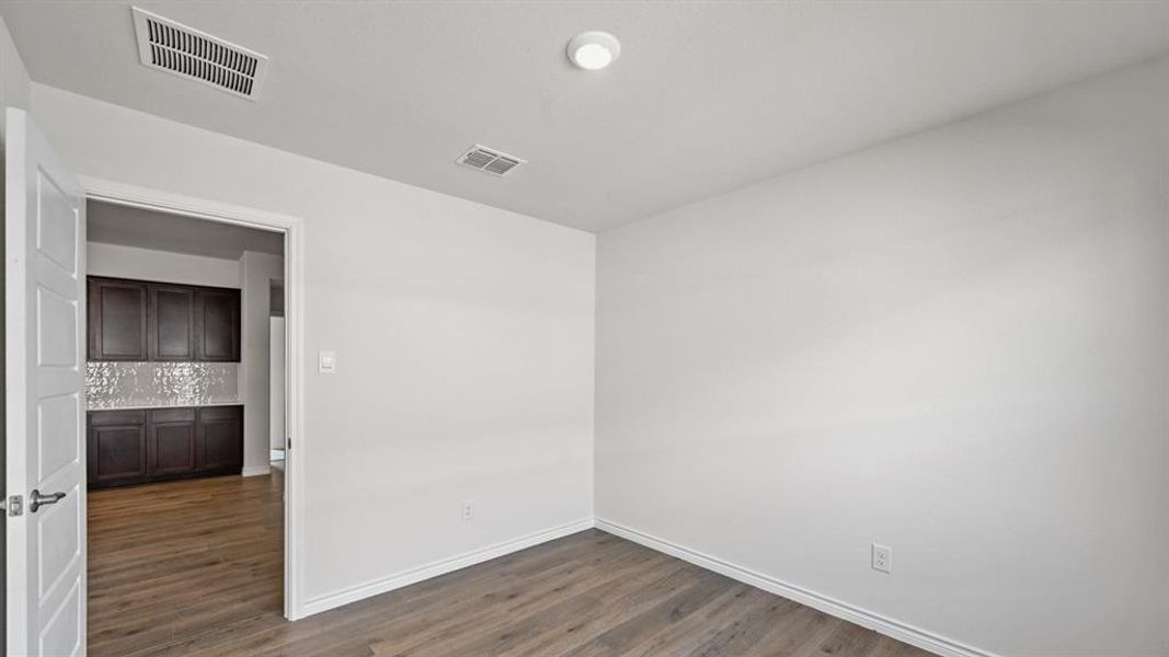 Spare room with baseboards and dark wood-style flooring
