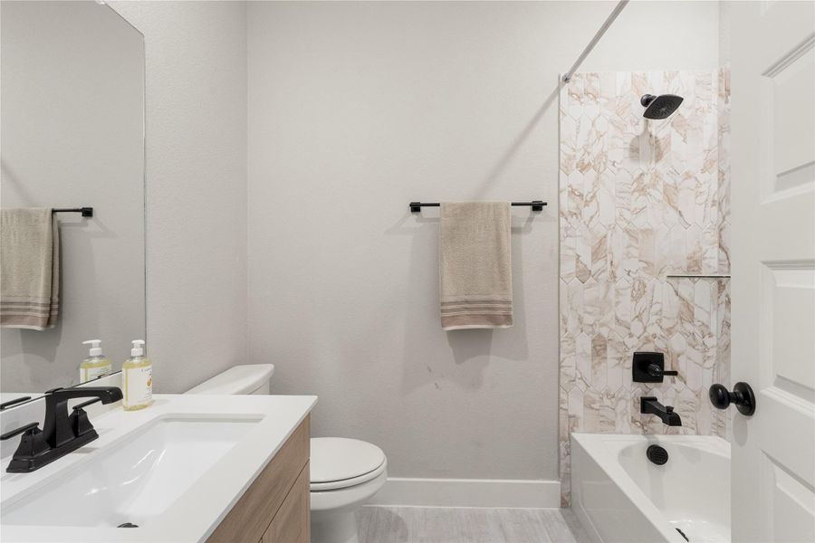 A well-appointed bathroom features a crisp white vanity, toilet, and bathtub, complemented by elegant patterned tile work. A well-appointed bathroom features a crisp white vanity, toilet, and bathtub, complemented by elegant patterned tile work.