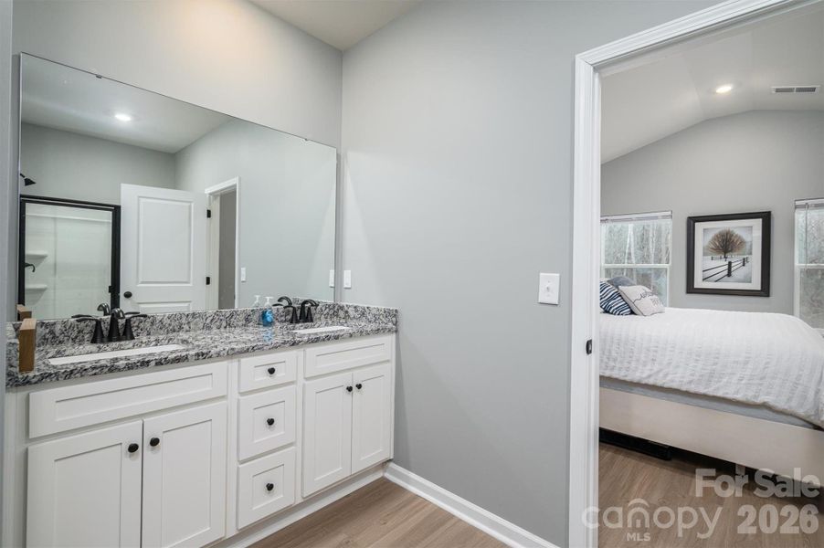 En-suite primary bath with double sink and granite counter tops