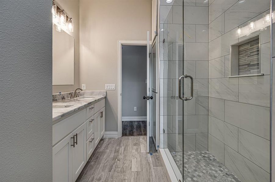 Bathroom featuring a shower with shower door, double sink vanity, and hardwood / wood-style floors