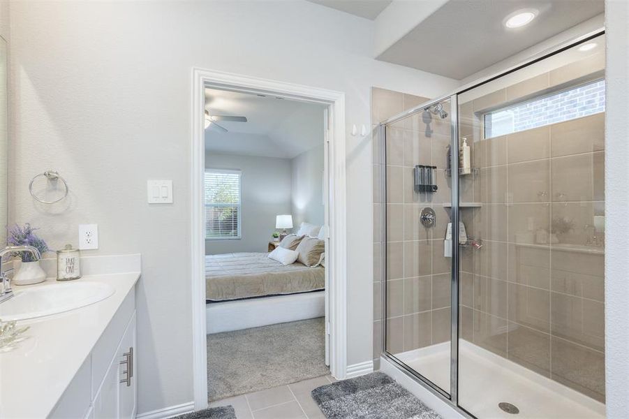 Ensuite bathroom featuring tile patterned flooring, a shower stall, vanity, and a ceiling fan Ensuite bathroom featuring tile patterned flooring, a shower stall, vanity, and a ceiling fan