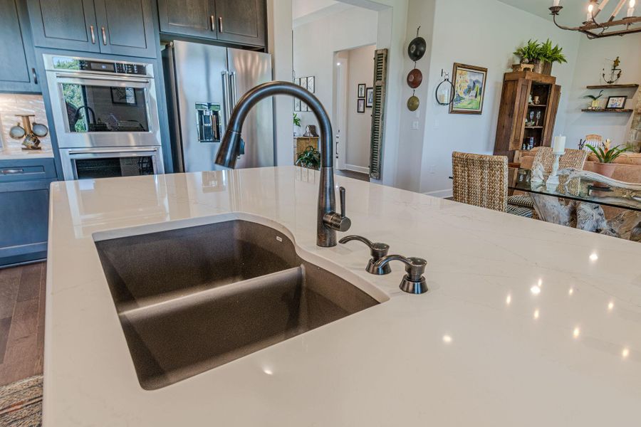Kitchen with appliances with stainless steel finishes, light stone countertops, and a chandelier
