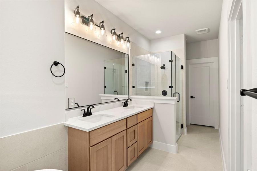Full bath with double vanity, a shower stall, light tile patterned flooring, and recessed lighting