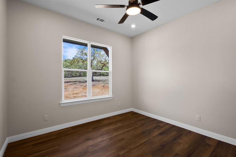 Empty room featuring baseboards, dark wood-style floors, and visible vents