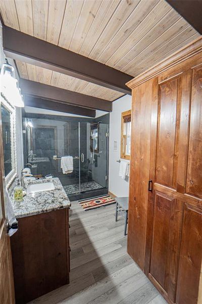 Full bathroom featuring a shower stall, vanity, light wood-type flooring, and beamed ceiling Full bathroom featuring a shower stall, vanity, light wood-type flooring, and beamed ceiling