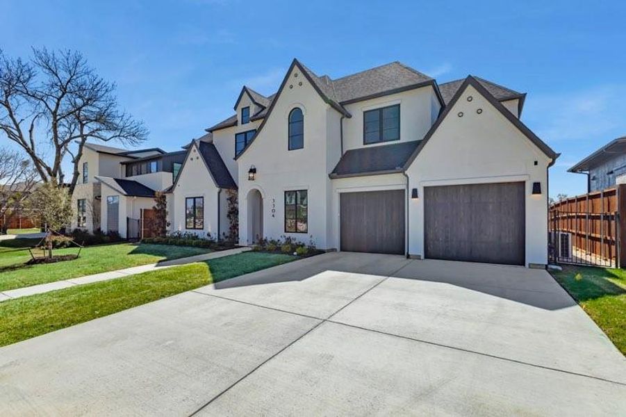 French country home featuring stucco siding, driveway, and a garage