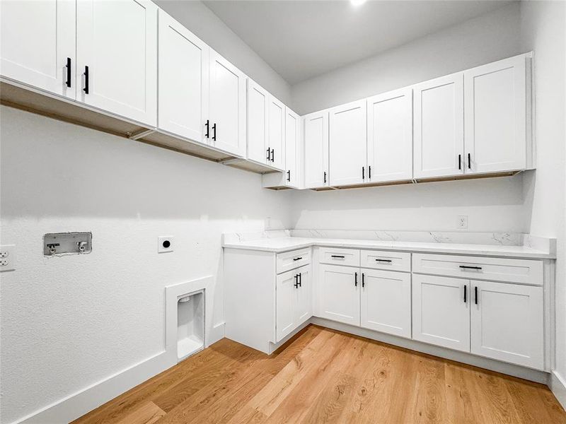 Laundry area with light wood-type flooring, cabinet space, hookup for a washing machine, and electric dryer hookup