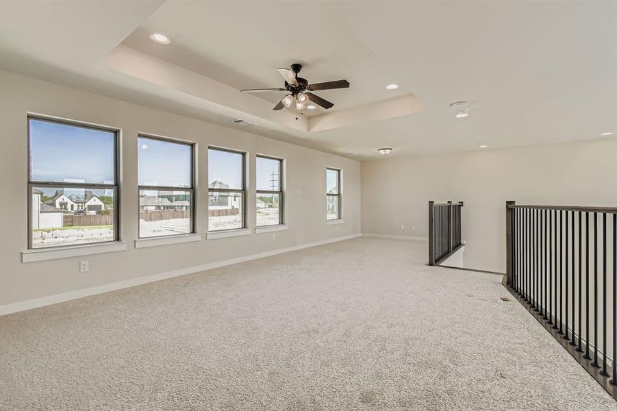 Empty room featuring a tray ceiling, ceiling fan, light colored carpet, and recessed lighting