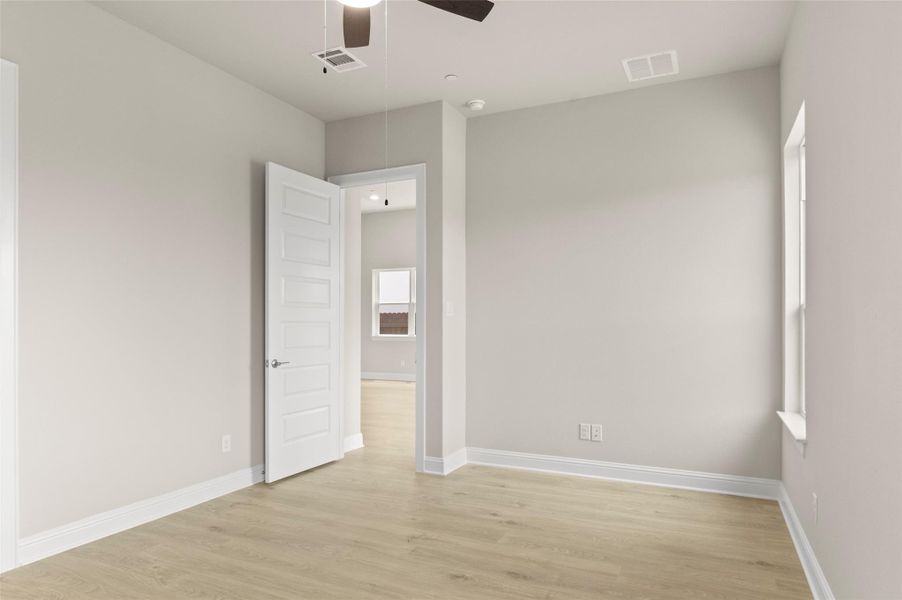 Spare room featuring attic access, light wood-type flooring, ceiling fan, and baseboards