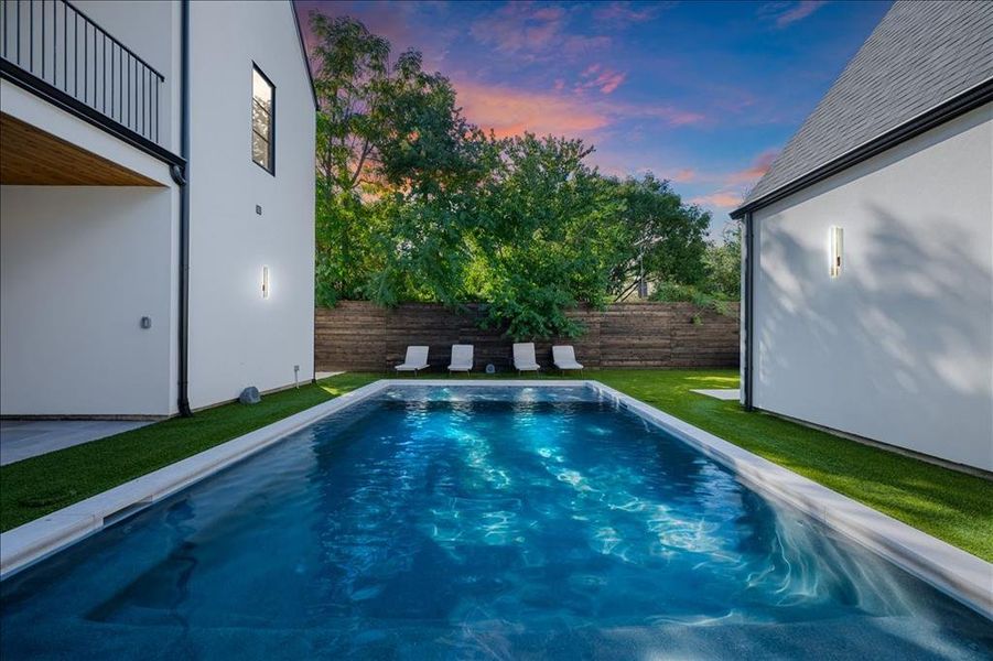 Heated pool at dusk featuring a fenced backyard and a patio