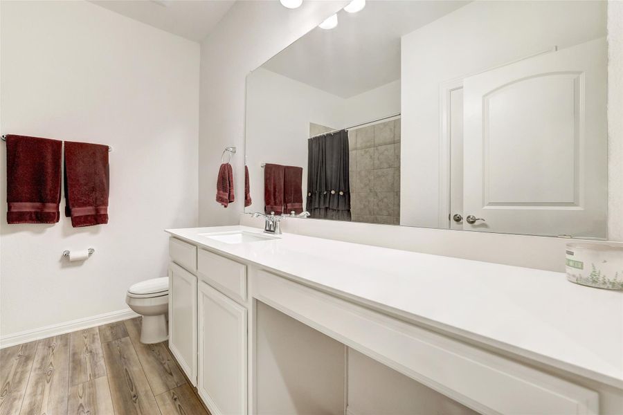 Bathroom featuring vanity, tiled shower, and wood finished floors