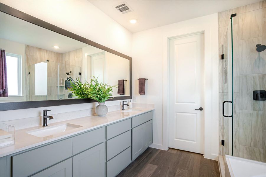 This modern bathroom features a double vanity with sleek fixtures, a large mirror, and a glass-enclosed shower. The space is bright and airy, with wood-style flooring and neutral tones for a contemporary feel. This modern bathroom features a double vanity with sleek fixtures, a large mirror, and a glass-enclosed shower. The space is bright and airy, with wood-style flooring and neutral tones for a contemporary feel.