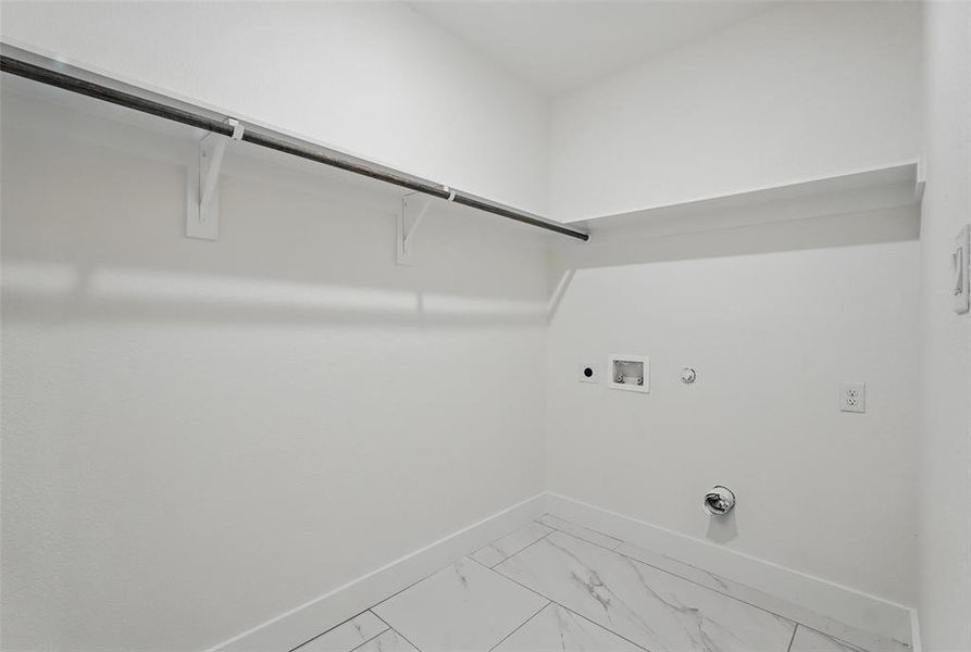 Clothes washing area featuring hookup for a gas dryer, electric dryer hookup, washer hookup, baseboards, and light marble finish flooring Clothes washing area featuring hookup for a gas dryer, electric dryer hookup, washer hookup, baseboards, and light marble finish flooring