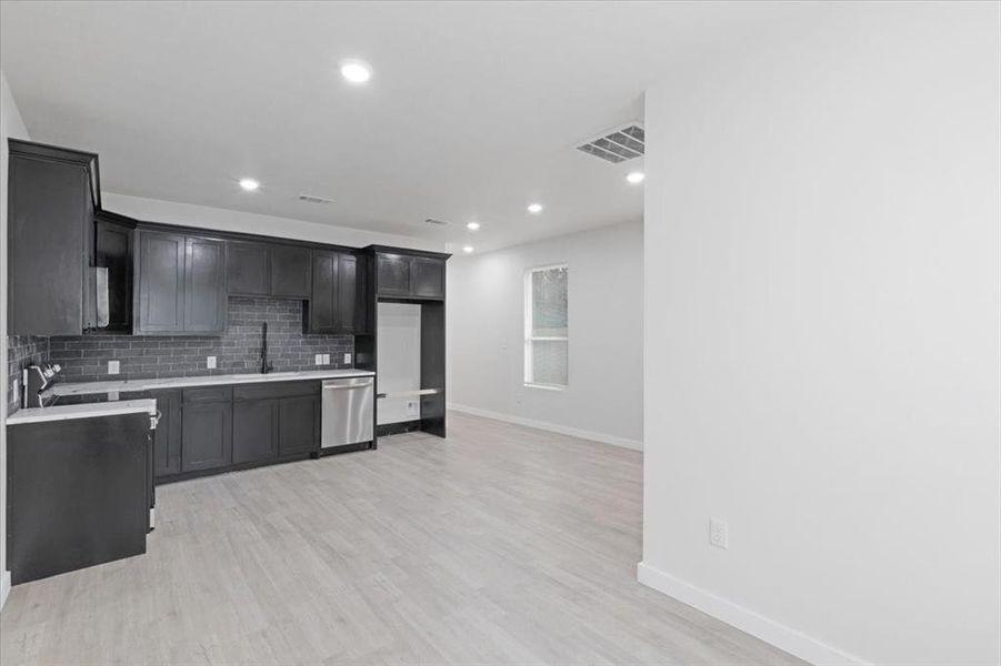 Kitchen with dishwasher, light wood-type flooring, sink, and tasteful backsplash