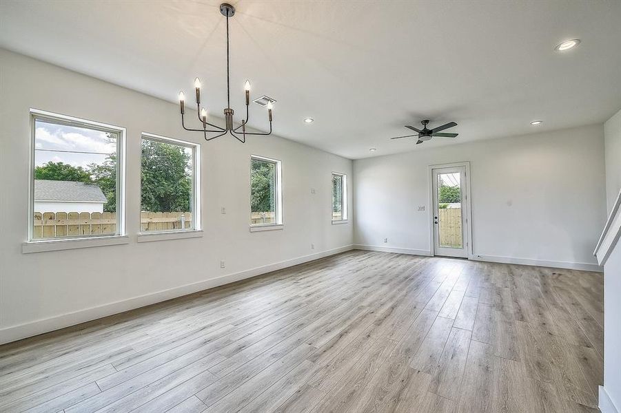 Spare room with ceiling fan with notable chandelier and light hardwood / wood-style floors