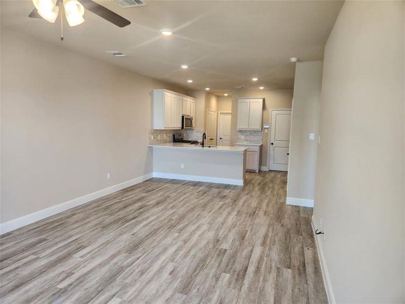 Kitchen featuring light hardwood / wood-style flooring, white cabinets, kitchen peninsula, backsplash, and ceiling fan