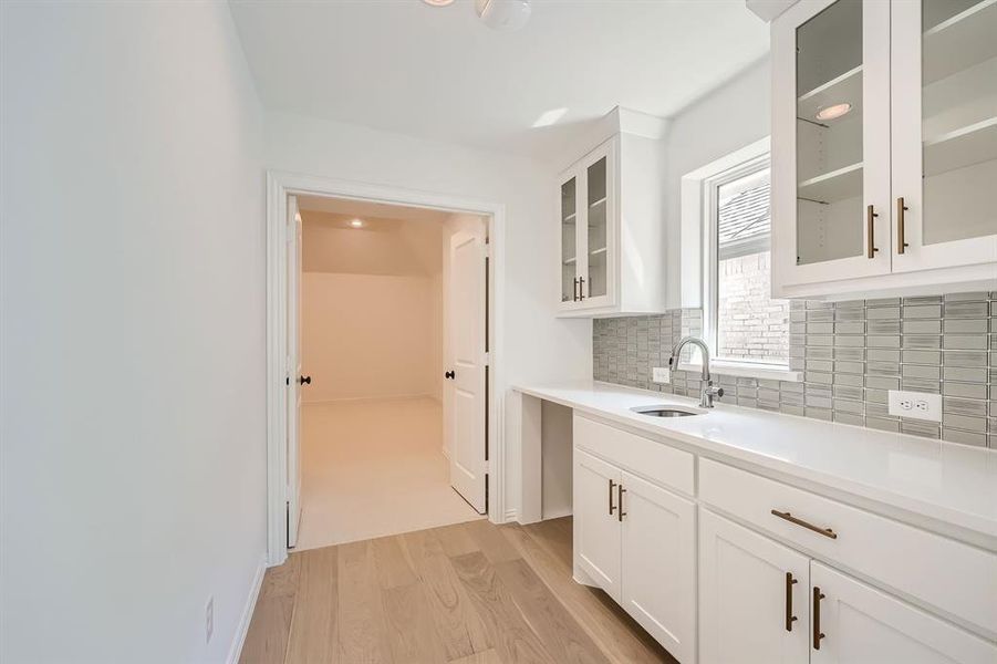 Kitchen featuring decorative backsplash, white cabinetry, light hardwood / wood-style floors, and sink