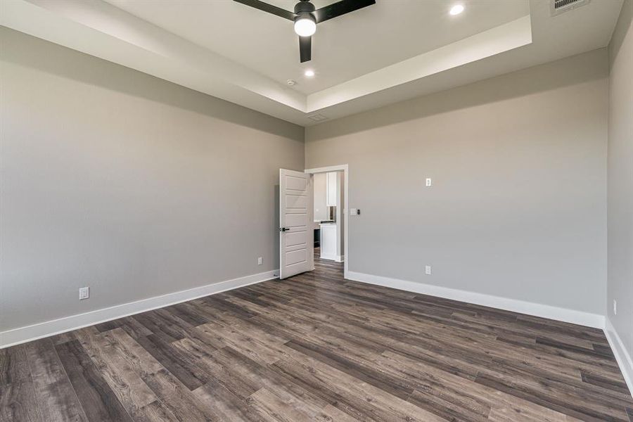 Spare room featuring ceiling fan, a tray ceiling, and dark hardwood / wood-style flooring