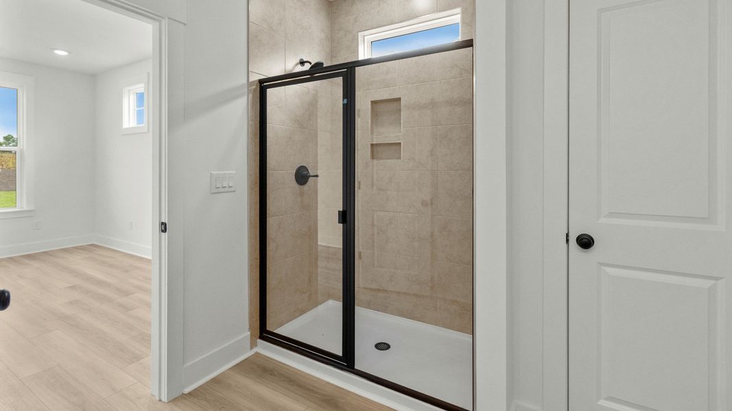 Luxury primary bath with walk-in tile shower at Chestnut Farms by DRB Homes