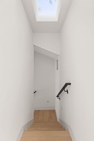 Stairs with a skylight and wood finished floors
