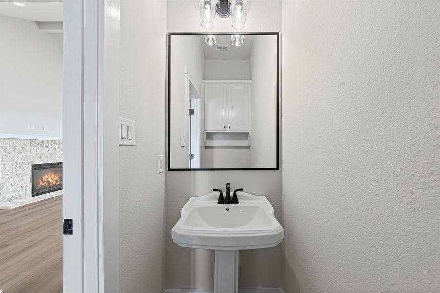 Bathroom featuring a stone fireplace, a textured wall, and wood finished floors