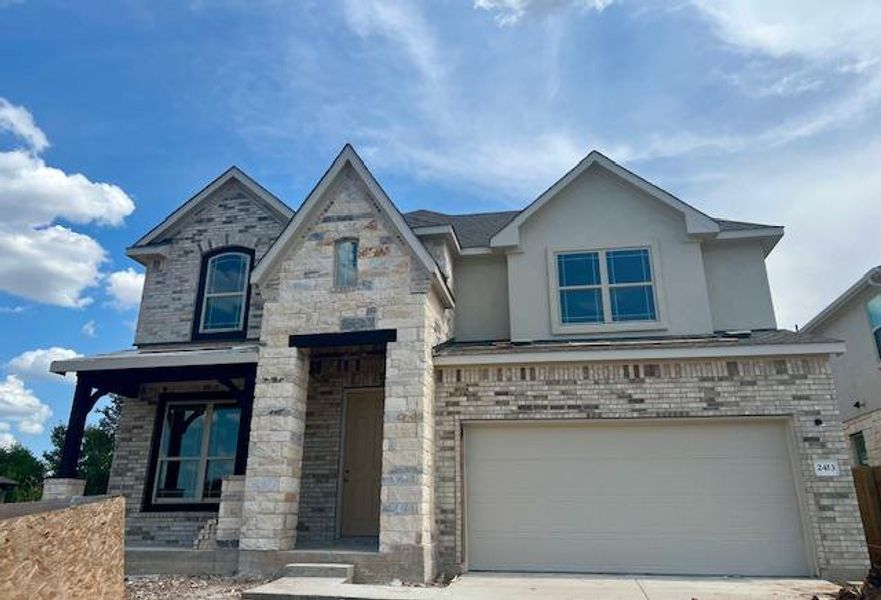 View of front of property featuring brick siding, an attached garage, driveway, stucco siding, and a porch View of front of property featuring brick siding, an attached garage, driveway, stucco siding, and a porch
