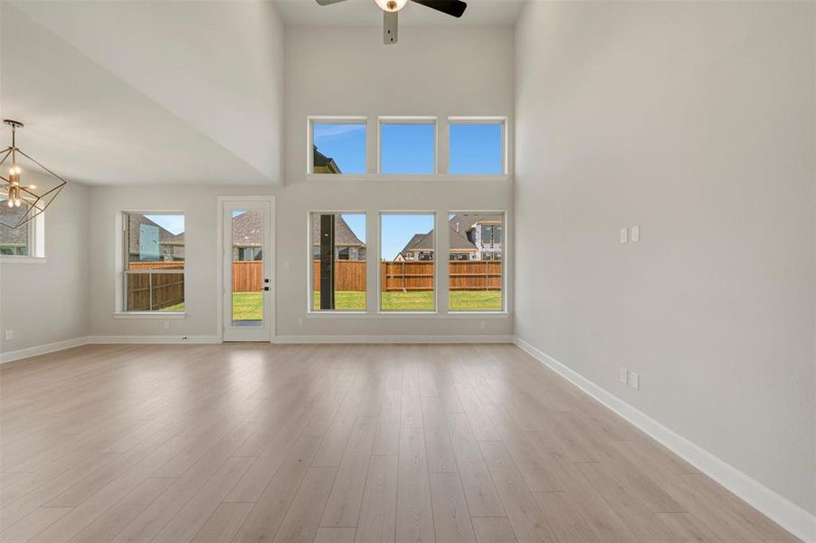 Spacious room featuring light wood-finish flooring, high vaulted ceilings, and a contemporary chandelier