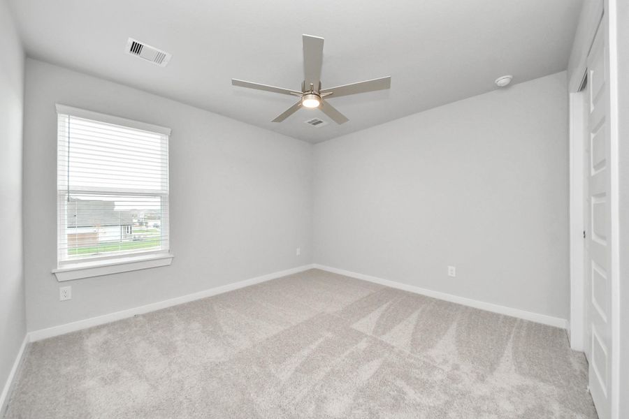 Secondary bedroom features plush carpeting, large windows that let in plenty of natural light, bright paint, and spacious closets.