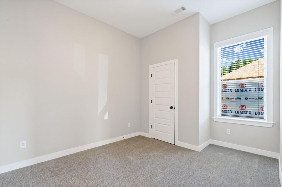 Carpeted room featuring light gray walls, white trim, and a white paneled door with a black knob