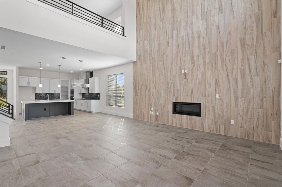 Unfurnished living room featuring a high ceiling and a glass covered fireplace Unfurnished living room featuring a high ceiling and a glass covered fireplace