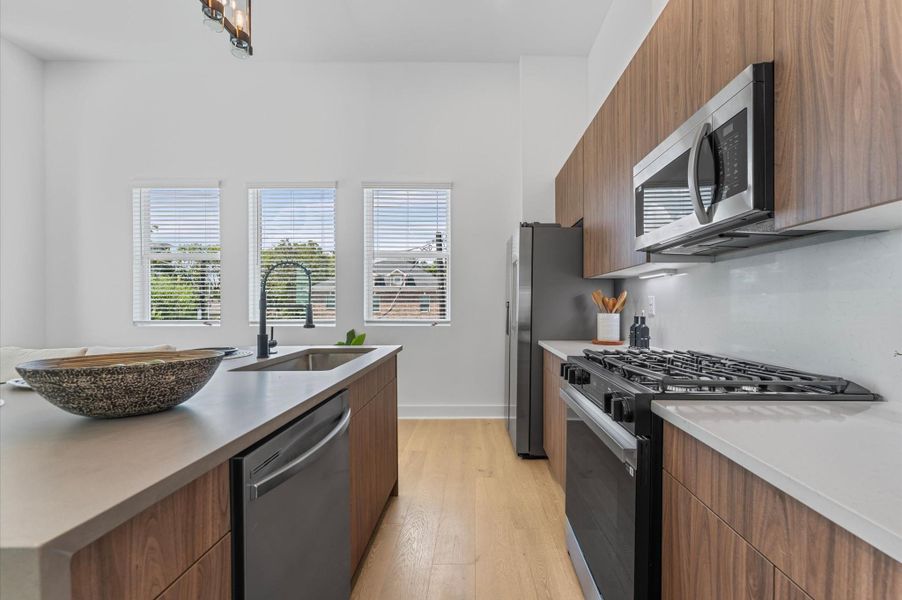 The kitchen is equipped with an abundance of sleek, modern cabinets, offering ample storage while maintaining a clean, contemporary look; perfect for keeping everything organized and stylish in the heart of the open concept living space.