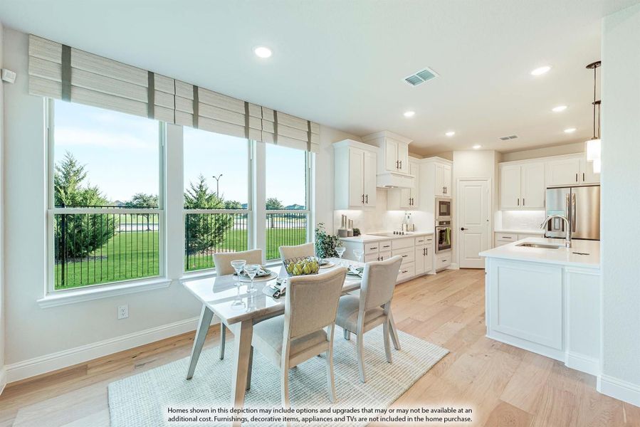 Open kitchen and dining area with white cabinets, stainless appliances, island, and large windows overlooking a yard