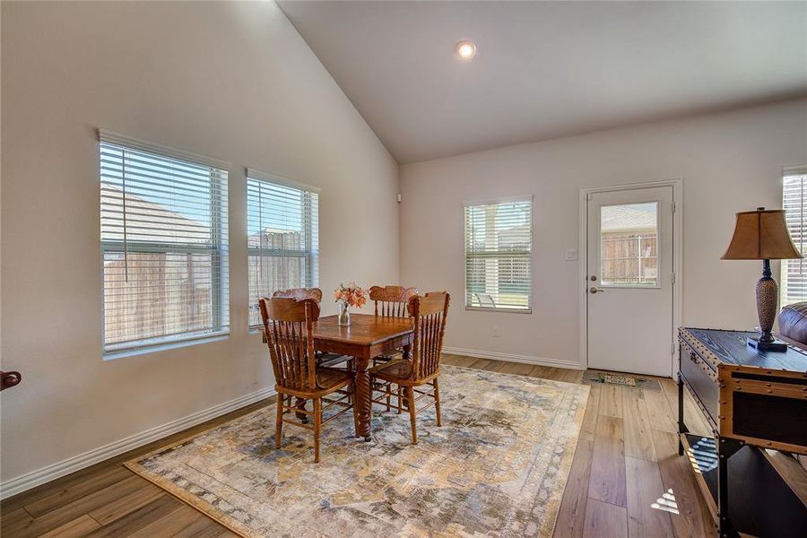 Dining space with hardwood / wood-style flooring, high vaulted ceiling, and a wealth of natural light