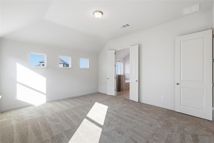 Unfurnished bedroom with light colored carpet, ensuite bathroom, and vaulted ceiling Unfurnished bedroom with light colored carpet, ensuite bathroom, and vaulted ceiling