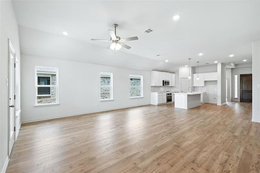 Unfurnished living room with light wood-type flooring, recessed lighting, a ceiling fan, and vaulted ceiling Unfurnished living room with light wood-type flooring, recessed lighting, a ceiling fan, and vaulted ceiling