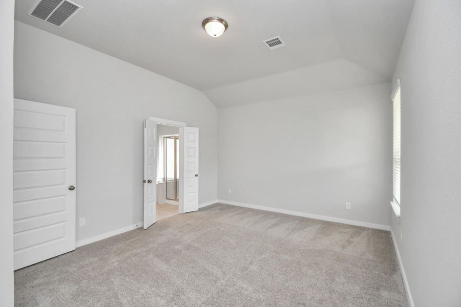 Escape and relax in the exquisite primary suite, a haven to unwind after a long day. The spacious room, boasts plush carpeting, soothing paint tones, high ceilings, and expansive windows adorned with privacy blinds. Sample photo of completed home with similar floor plan. Actual colors and selections may vary.