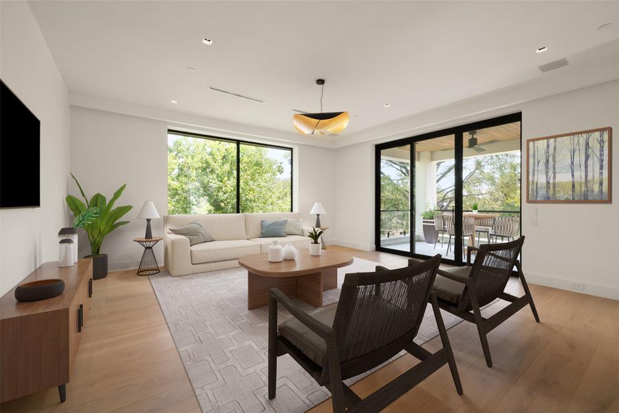 Living area with light wood-style flooring and recessed lighting, virtually staged