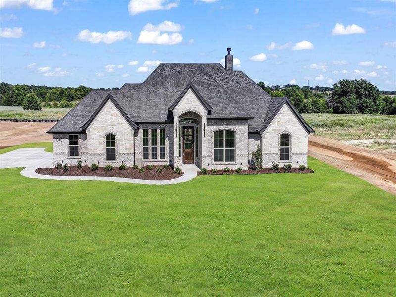 French provincial home featuring stone siding, brick siding, a chimney, and a front lawn French provincial home featuring stone siding, brick siding, a chimney, and a front lawn