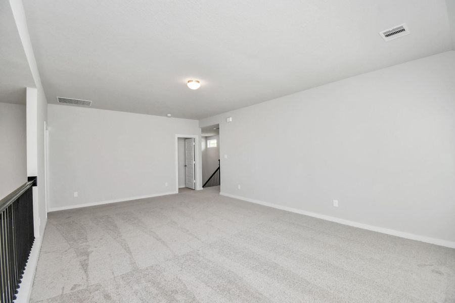 Come upstairs and enjoy a day of leisure in this fabulous game room! This is the perfect hangout spot or adult game room! Features plush carpet, high ceilings, custom paint and windows for plenty of natural light. Sample photo of completed home with similar floor plan. Actual colors and selections may vary.