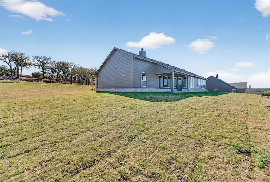 Back of property featuring a lawn, a patio area, and a chimney Back of property featuring a lawn, a patio area, and a chimney