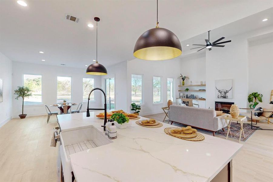 Kitchen with decorative light fixtures, a healthy amount of sunlight, and a center island with sink