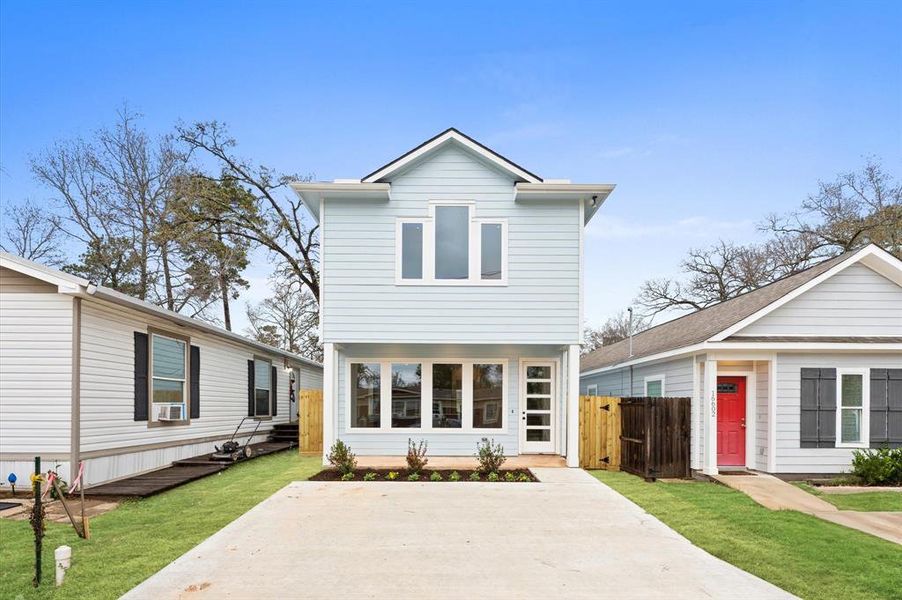 Charming two-story home with a modern facade, featuring large windows and a clean, light blue exterior. The property includes a spacious driveway in a cozy neighborhood setting.