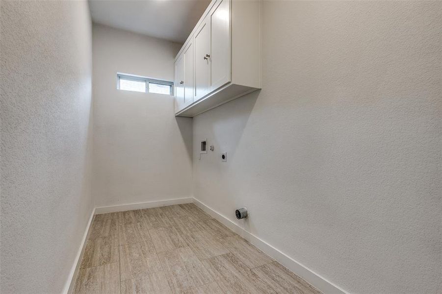 Laundry room featuring light hardwood / wood-style flooring, hookup for a washing machine, electric dryer hookup, and cabinets