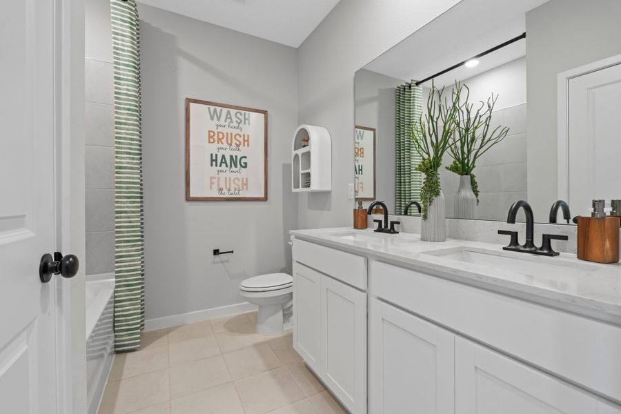 A bathroom with a sink toilet and a mirror.