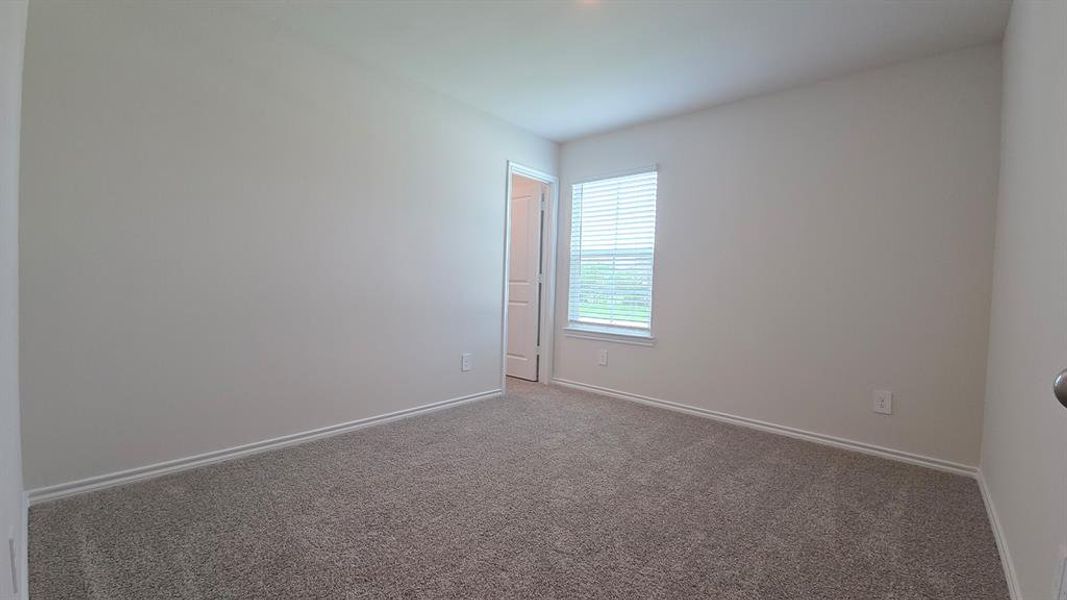 Spacious room featuring neutral carpeting, light-toned walls, and a window with horizontal blinds Spacious room featuring neutral carpeting, light-toned walls, and a window with horizontal blinds