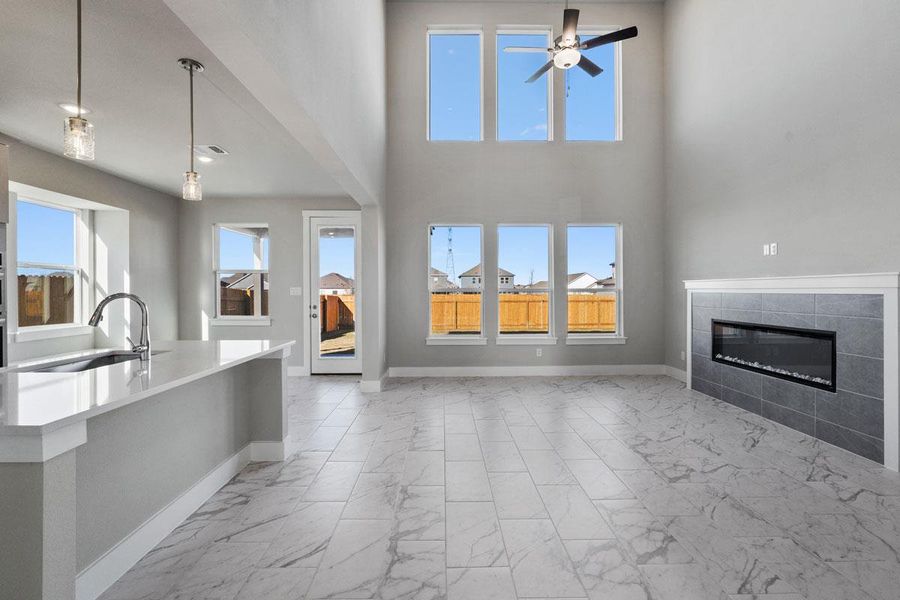 Soaring ceilings and marble-look tile flooring frame this open-concept living area with a sleek fireplace. Soaring ceilings and marble-look tile flooring frame this open-concept living area with a sleek fireplace.